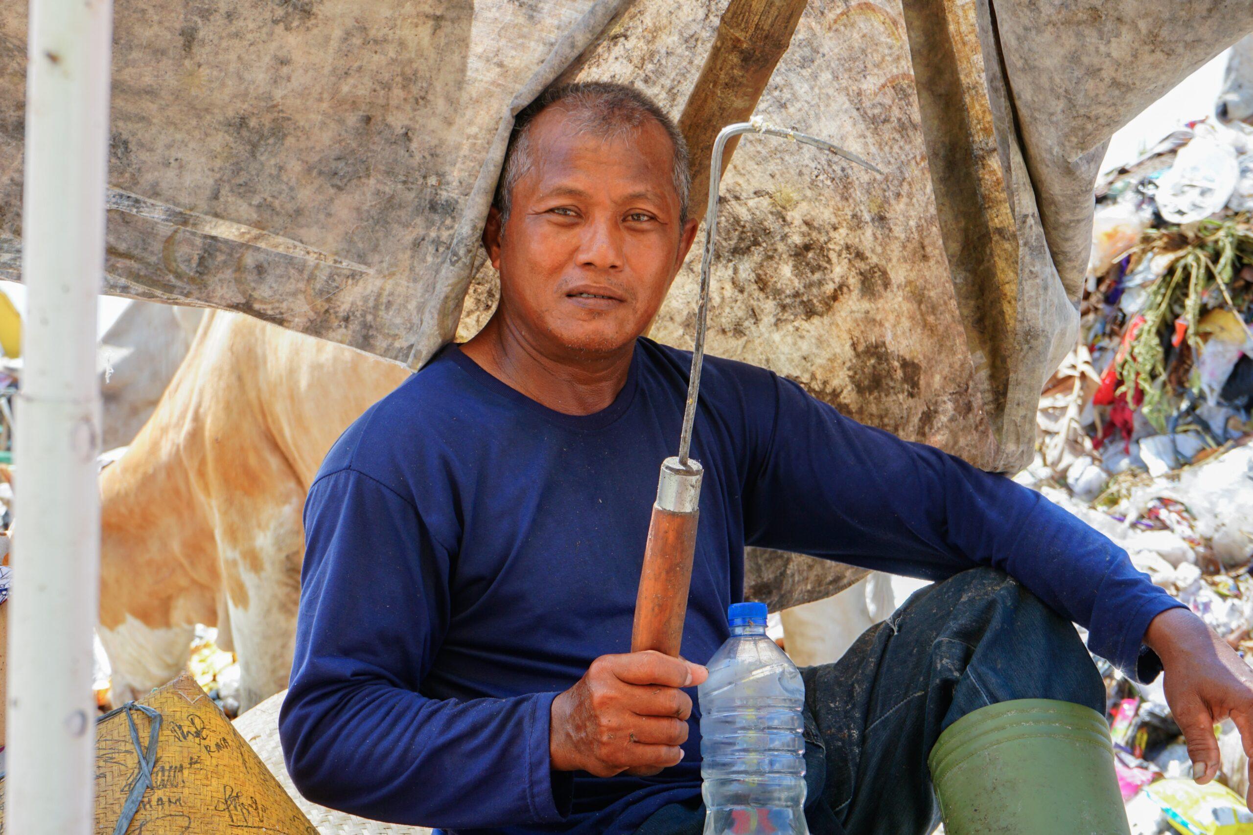Daliman (60) salah satu pemungut sampah untuk pakan lele sedang meneduh sambil mengangkat tongkat sampah. Foto: Himmah/Eka Ayu Safitri